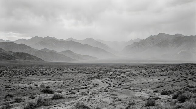 Desolate mountain basin and dry plains in atmospheric black-and-white, fine-art landscape photography, layered gray ridges, low contrast haze, broad horizontal composition, austere natural texture,