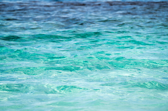 Vibrant two tone ocean water surface showing transition between deep dark blue sea and bright turquoise waves on sunny day
