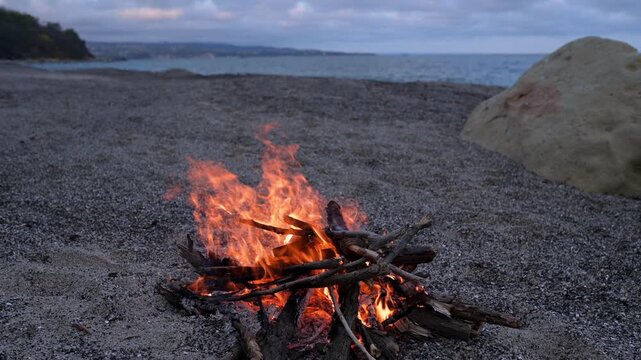 Bonfire Burning on Pebble Beach at Dusk with Sea Waves Sound