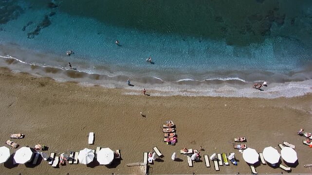 Aerial view of a tropical beach resort with tourists swimming and sunbathing