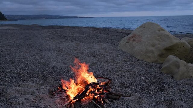 Bonfire Burning on Pebble Beach at Dusk with Sea Waves Sound