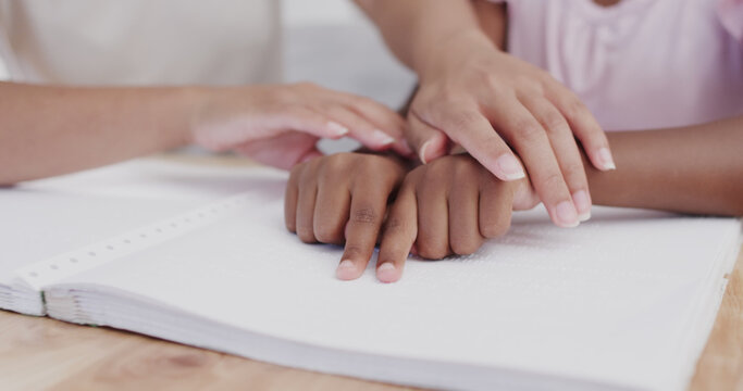mother and daughter reading book written in braille