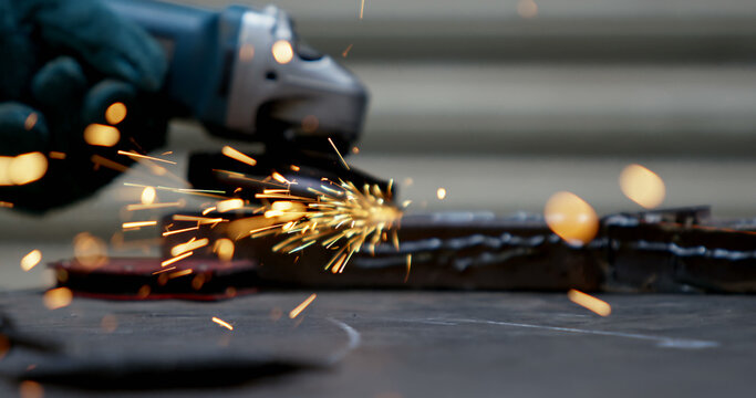 Close-up of a worker using an angle grinder on metal at a construction site