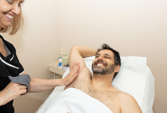 Man receiving professional armpit waxing hair removal treatment