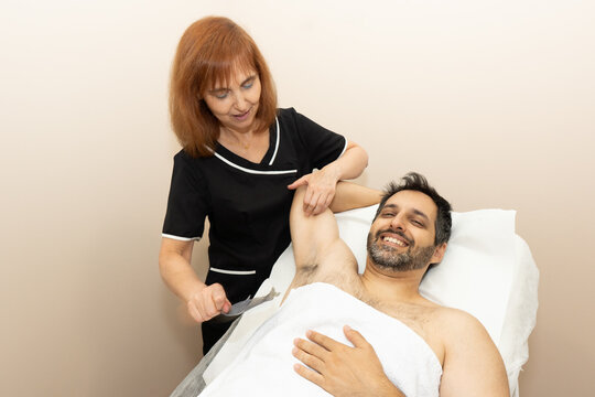 Man getting underarm waxing at beauty salon