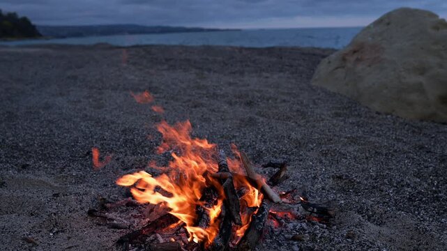 Bonfire Burning on Pebble Beach at Dusk with Sea Waves Sound