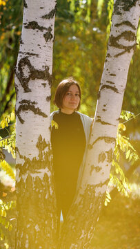 Woman stands between two birch trees