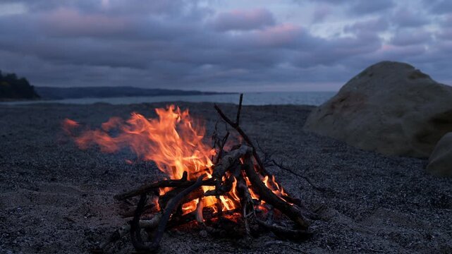 Bonfire Burning on Pebble Beach at Dusk with Sea Waves Sound