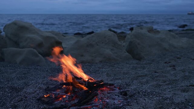 Bonfire Burning on Pebble Beach at Dusk with Sea Waves Sound