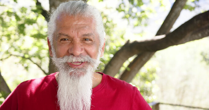Portrait of happy senior man with white beard in sunny nature, copy space, slow motion