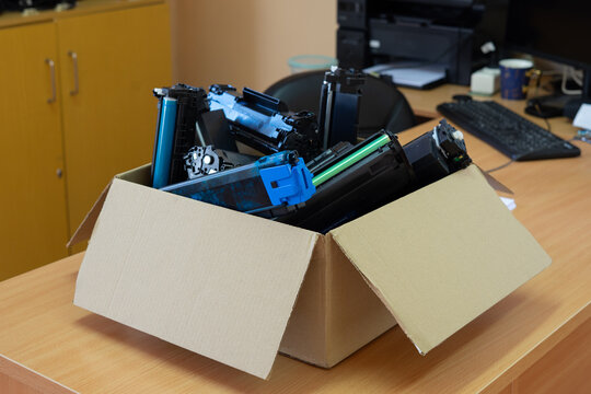 Box of used toner cartridges for recycling in office environment