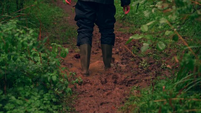 Man walking through deep woodland mud in wellington boots
