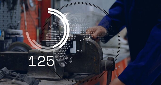 Clamping metal piece, worker in blue coverall operating bench vise on bench, HUD showing India 125