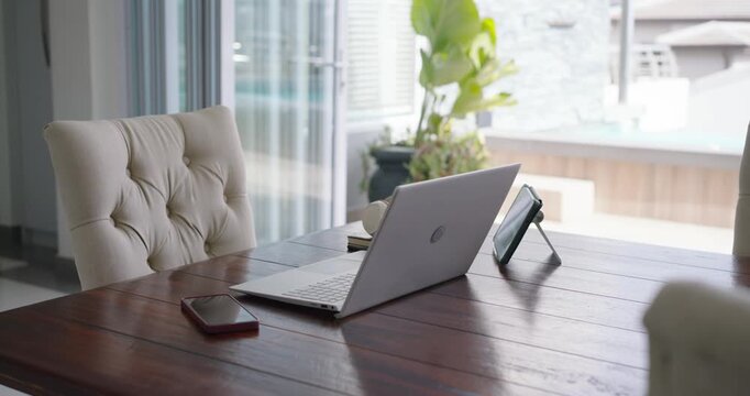 Camera is sliding left and forward after start, bringing laptop on wooden table into focus