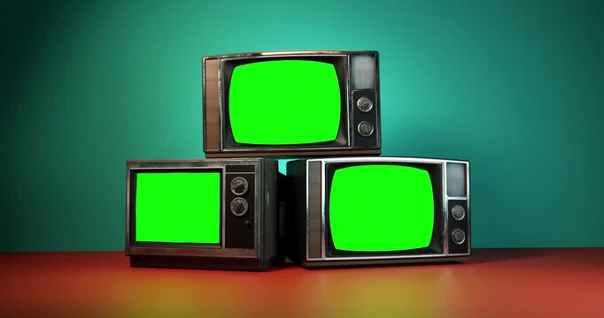 Camera pulling back from stack of three vintage retro televisions turning on to reveal blank green screens in colorful room