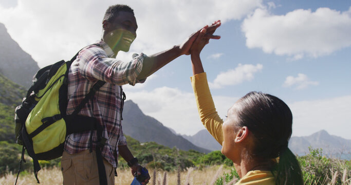 African american couple high fiving each other while trekking in the mountains