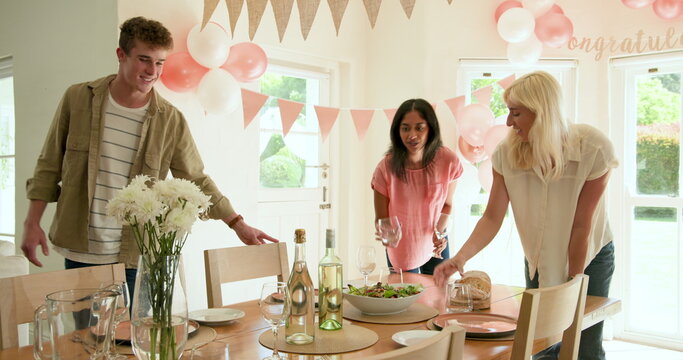 Happy white and multiracial friends preparing plates and decorations for party at home with congratu