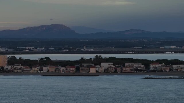 Carnon beach houses with lagoon and mountains at dusk