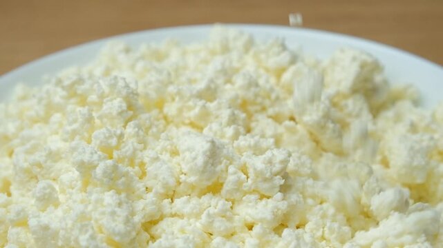 Organic curd cheese pouring from spoon slow motion