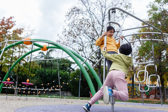 Two Children Playing on Playground Climbing Equipment in Autumn