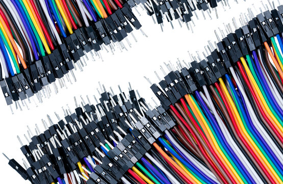 Colorful jumper cables with male connector pins arranged around white copy space, electronic wiring for breadboard circuits, microcontrollers, robotics, automation, engineering and technology projects
