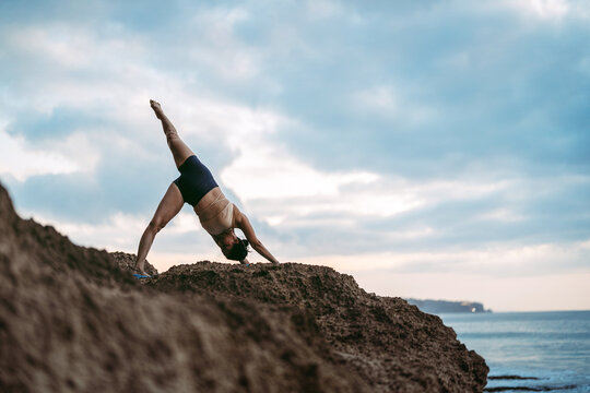 Asian woman practicing yoga on a tropical beach during a relaxing vacation retreat
