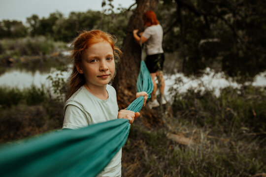 Redhead girl with turquoise hammock by lake