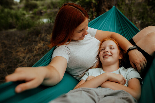 Mother and daughter lying in hammock, top view