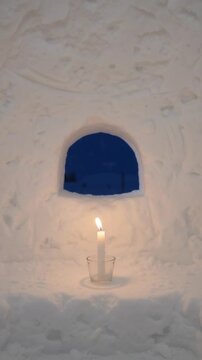 Candle glowing inside a kamakura snow hut on a winter night, vertical background for snow festival and winter travel promotions