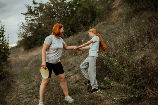 Mother and daughter playing tug in field, laughing