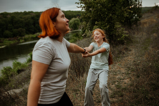 Laughing mother and daughter holding hands outdoors