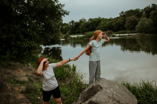 Mother and daughter holding hands on lake shore