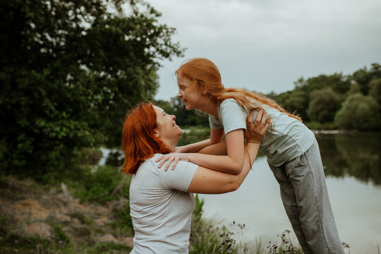 Laughing mother and daughter face to face by lake