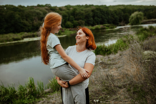 Mother lifting daughter on lake shore