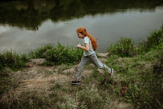 Redhead girl running along lake shore