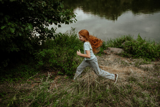 Girl running on grassy shore by water