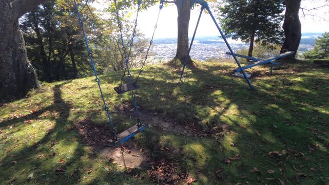 Empty swings and playground equipment on a hill overlooking a Japanese town