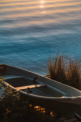 Rowboat on a lakeshore beside sunlit grasses and rippling water © Vadim