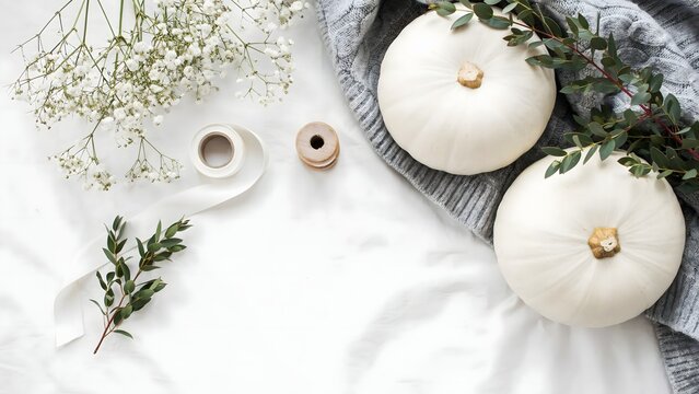 White pumpkins autumn decor with greenery and ceramic mugs on neutral cloth