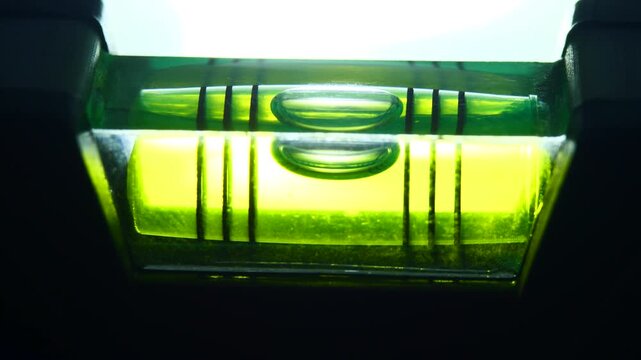 Extreme close up luminous neon green bubble spirit level vial showing perfect balance. Ideal for residential construction company web banner, interior renovation service, precision engineering promo