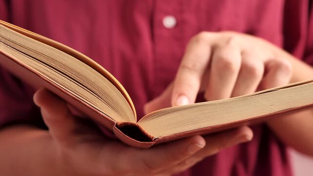 Close up of hands folding page corner inside textbook before closing it. Perfect for university student library app promotion, paperback publishing house commercial or private bookstore banner