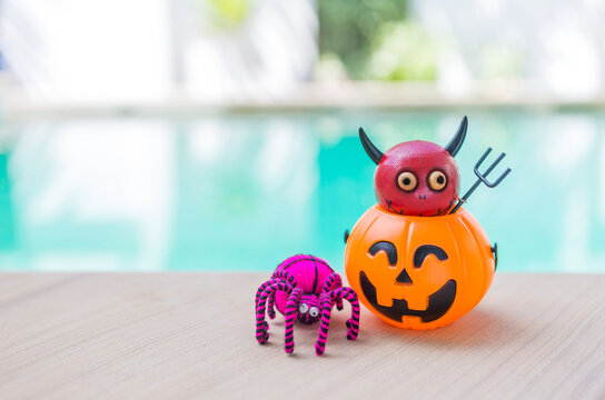 Red devil in Halloween lantern and pink wool spider over blurred background, Halloween card background idea