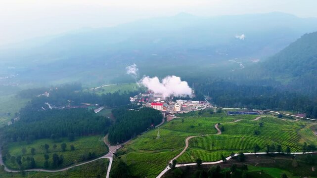 Aerial view of PLTA Lamajan hydroelectric power plant with surrounding lush green forests and river in Pangalengan, West Java, Indonesia.