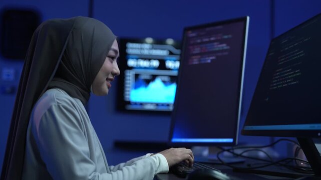 Muslim female developer wearing hijab coding on computer in modern office, Asian professional woman working on software development, Tech industry diversity and corporate programming business concepts