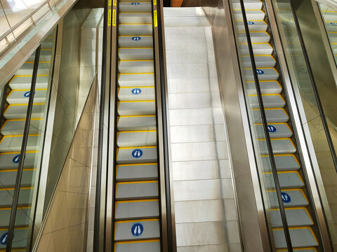 Parallel escalators with yellow-edged steps descend through a bright interior, illustrating pedestrian circulation in a large public building