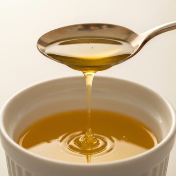 Metal spoon dripping golden melted butter into white ceramic ramekin bowl