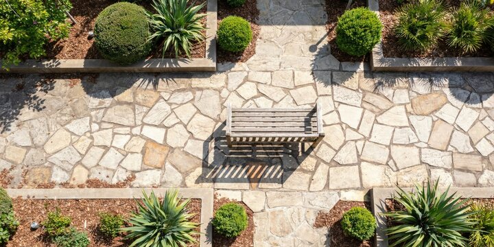 Top-down view of a stone-paved garden path with a wooden bench and manicured shrubs