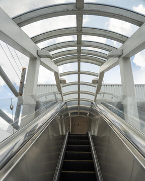 Empty Escalator Beneath a Curved Glass Canopy