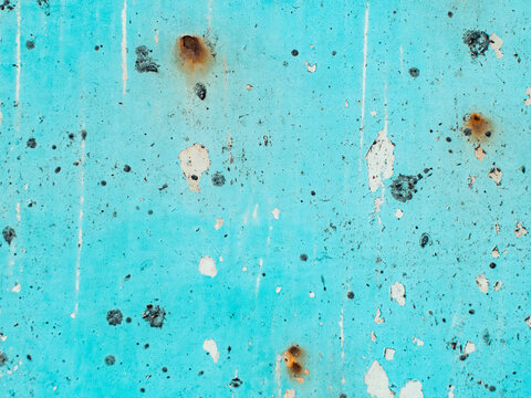 Weathered turquoise painted metal wall with peeling paint, rust spots and black speckles, grunge texture background showing decay and age, distressed aqua surface with white undercoat