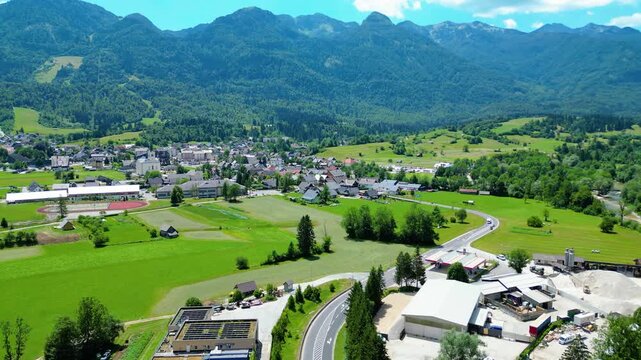 Lush Julian Alps valley in Slovenia, with a charming village, winding river, and majestic peaks under a bright summer sky. An idyllic scene for nature and travel. Bohinjska Bistrica